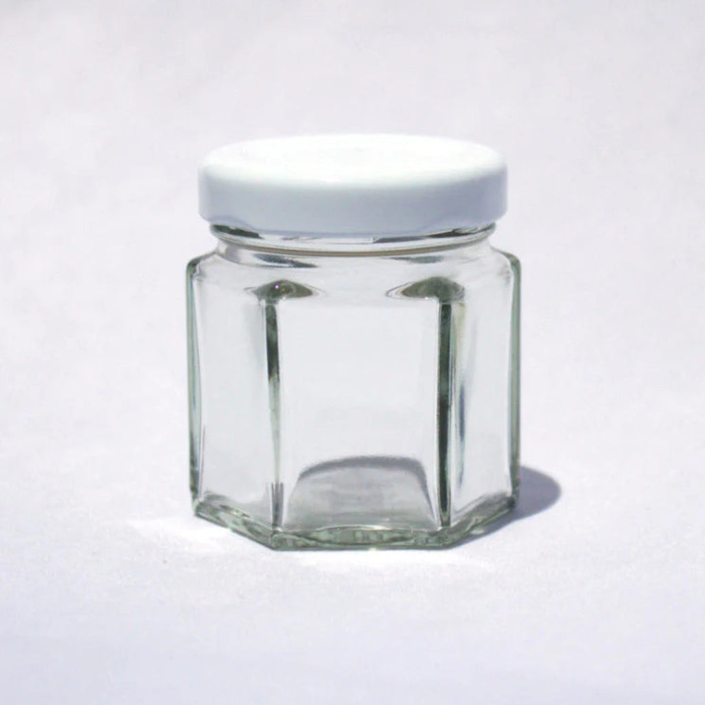 Hexagonal glass jar with a white lid on a white background