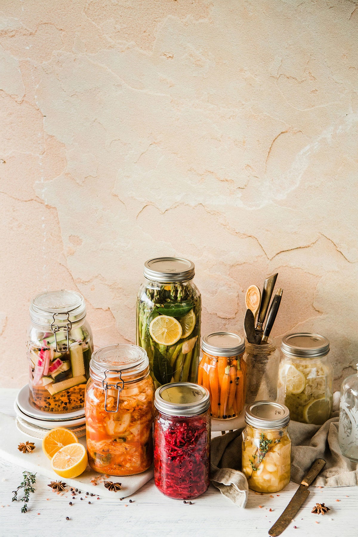 Collection of glass jars with preserved foods on a light stone background